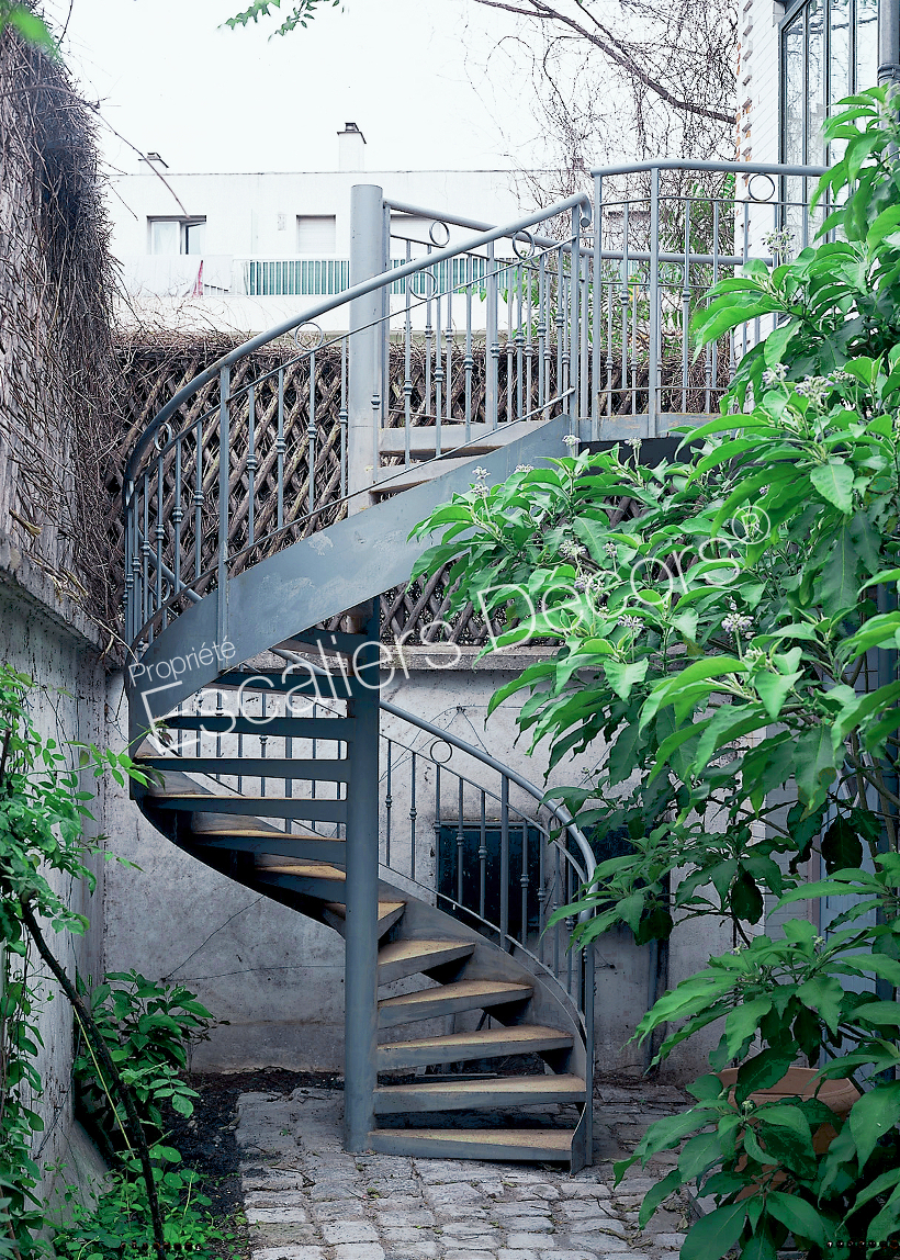 Photo DH11 - SPIR'DÉCO® Caisson. Escalier extérieur métallique hélicoïdal avec rampe à l'ancienne en fer forgé pour relier le jardin au balcon.