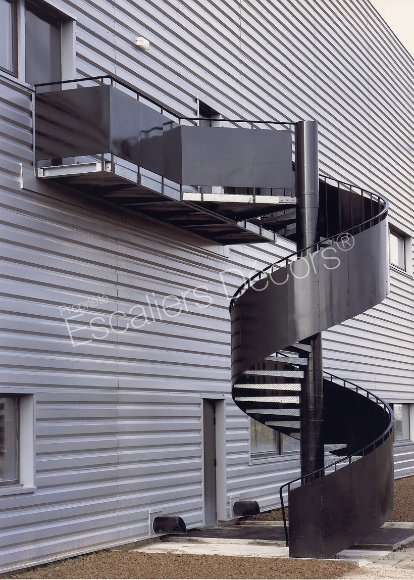 IH14 - Colimaçon Larmé de la Collection Édouard. Escalier extérieur hélicoïdal en acier installé dans des entrepôts.