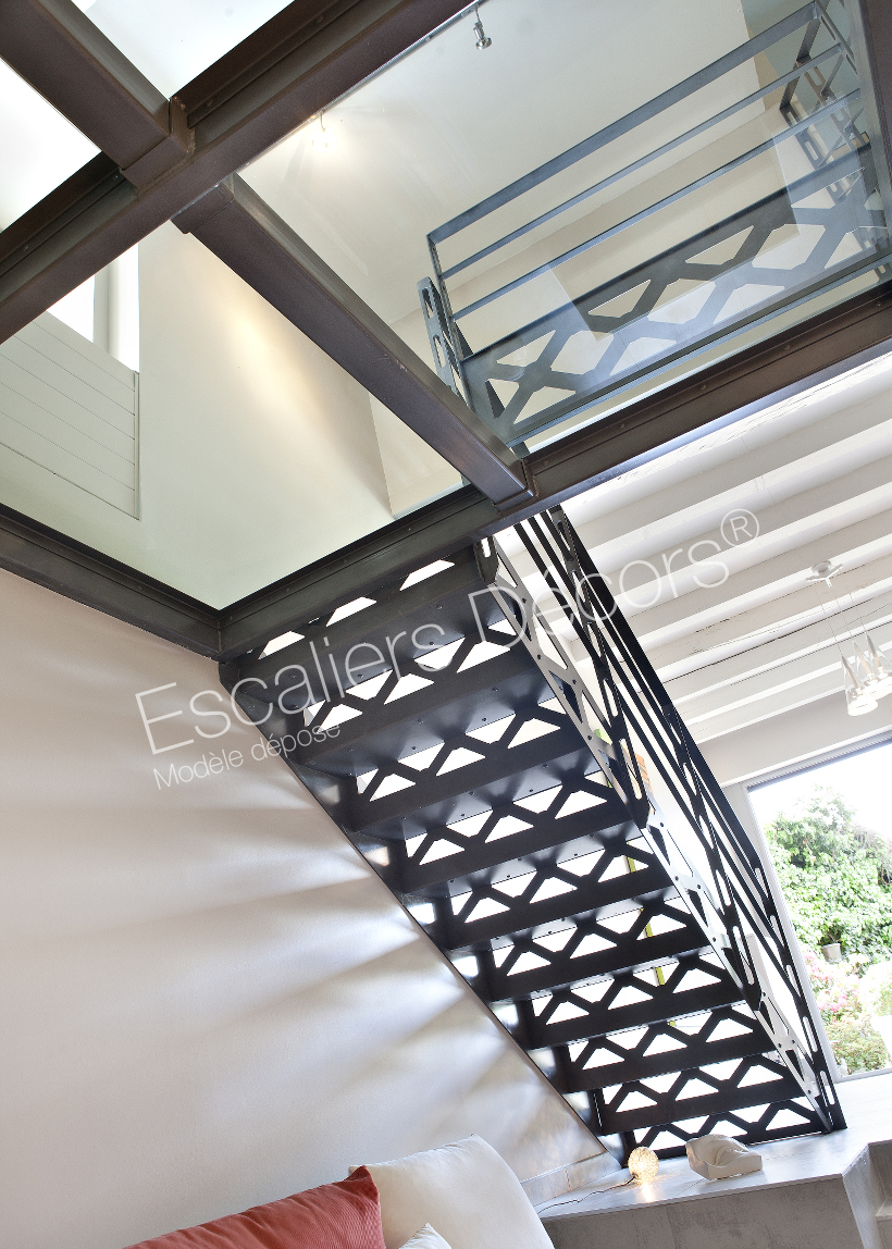 Escalier au design industriel avec contremarches ajourées. Modèle San Francisco d'Escaliers Décors. Marches en métal insonorisées. Plancher en verre avec structure acier.