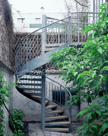 DH11 - SPIR'DÉCO® Caisson. Escalier extérieur métallique hélicoïdal avec rampe à l'ancienne en fer forgé pour relier le jardin au balcon.
